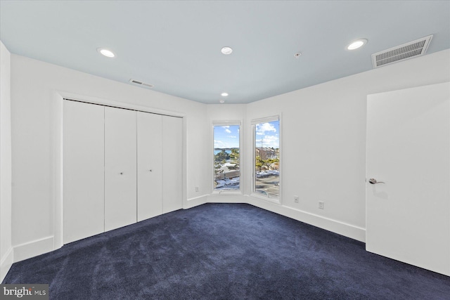 unfurnished bedroom featuring a closet and dark colored carpet