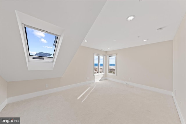 spare room featuring light colored carpet and vaulted ceiling with skylight