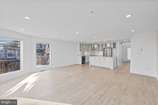 unfurnished living room with sink and light hardwood / wood-style floors