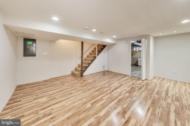 basement featuring electric panel and light hardwood / wood-style floors