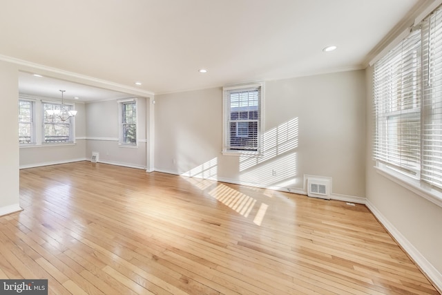 spare room with light hardwood / wood-style floors, plenty of natural light, crown molding, and a chandelier