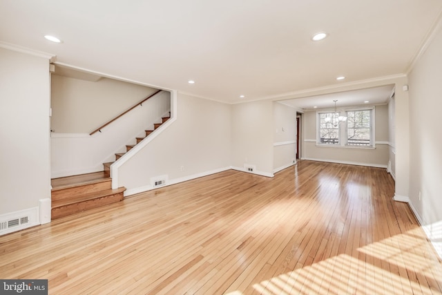 unfurnished living room with an inviting chandelier, ornamental molding, and hardwood / wood-style flooring