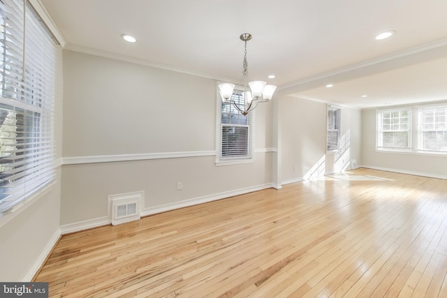 unfurnished dining area featuring light hardwood / wood-style floors, ornamental molding, and a chandelier