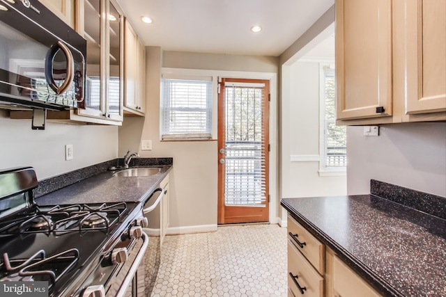 kitchen featuring stainless steel gas stove, sink, and dark stone counters