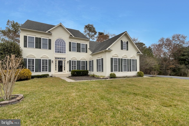 rear view of property with a yard and roof with shingles