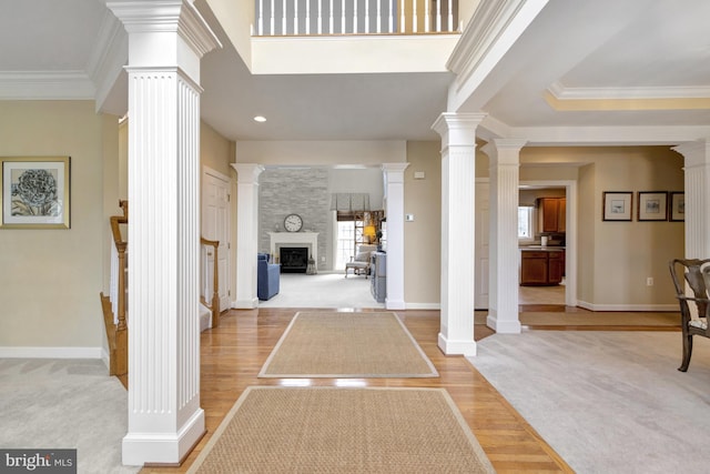 entrance foyer with baseboards, light wood-style floors, ornate columns, and ornamental molding