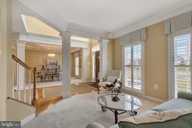 living area featuring ornamental molding, wood finished floors, baseboards, and decorative columns