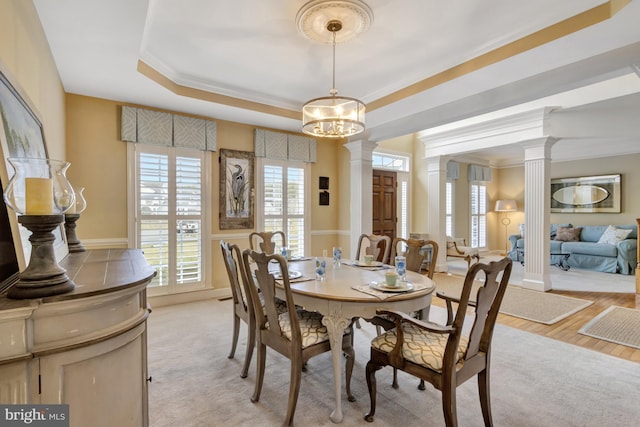 dining room featuring a chandelier, crown molding, a raised ceiling, and decorative columns