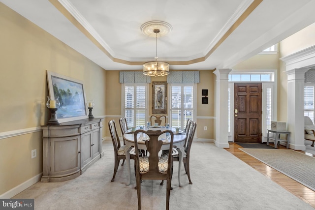 dining space with a notable chandelier, ornamental molding, a tray ceiling, baseboards, and ornate columns