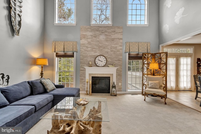 living area with a tiled fireplace, carpet, and a wealth of natural light