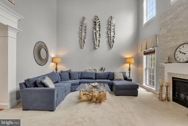 living area featuring a fireplace with flush hearth, a towering ceiling, and carpet flooring