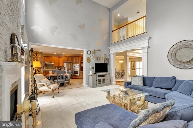 living room with decorative columns, light colored carpet, a high ceiling, and a fireplace