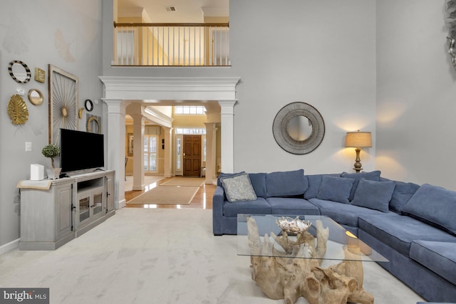 living room featuring visible vents, a high ceiling, carpet, decorative columns, and baseboards