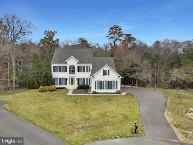 view of front of home with driveway, a front lawn, and roof with shingles