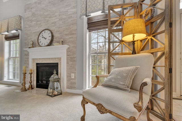 living area with carpet flooring, a glass covered fireplace, plenty of natural light, and a towering ceiling