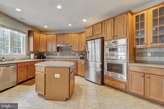 kitchen with under cabinet range hood, light tile patterned floors, appliances with stainless steel finishes, and light countertops