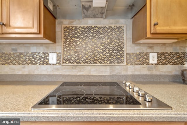 kitchen featuring tasteful backsplash, light countertops, and black electric stovetop