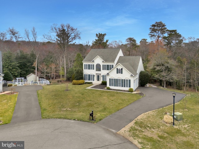 view of front of property featuring a front lawn, an attached garage, and driveway