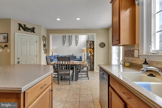 kitchen featuring backsplash, light tile patterned floors, brown cabinets, stainless steel dishwasher, and a sink