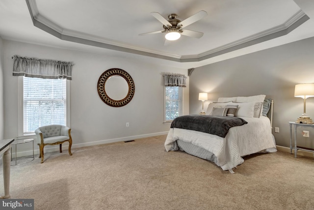 carpeted bedroom featuring a tray ceiling, baseboards, and crown molding