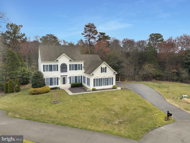 view of front of house featuring aphalt driveway, a shingled roof, and a front lawn