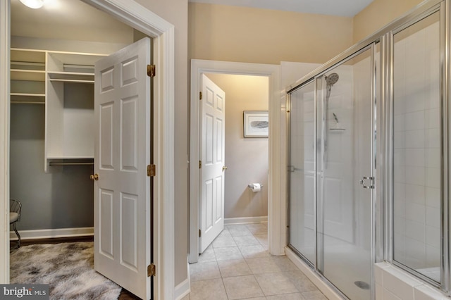 bathroom with a shower stall, a closet, baseboards, and tile patterned floors