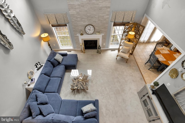 living area featuring tile patterned floors, baseboards, a high ceiling, and a fireplace