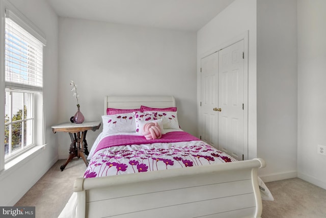 carpeted bedroom featuring multiple windows, baseboards, and a closet