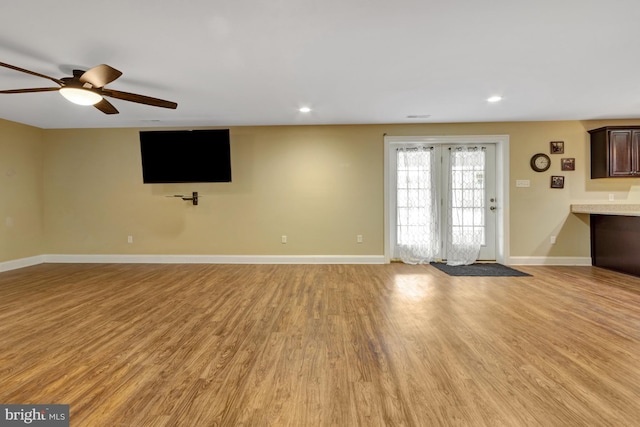 unfurnished living room with recessed lighting, light wood-style floors, and baseboards