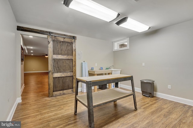 dining area with a barn door, light wood-style floors, and baseboards