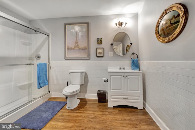 full bath featuring toilet, wood finished floors, wainscoting, a shower stall, and vanity