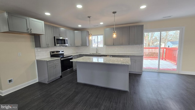 kitchen featuring pendant lighting, gray cabinetry, sink, appliances with stainless steel finishes, and a kitchen island