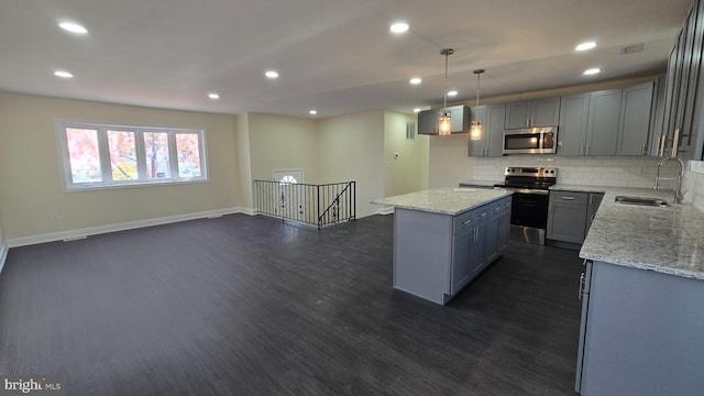 kitchen featuring sink, pendant lighting, decorative backsplash, a kitchen island, and appliances with stainless steel finishes