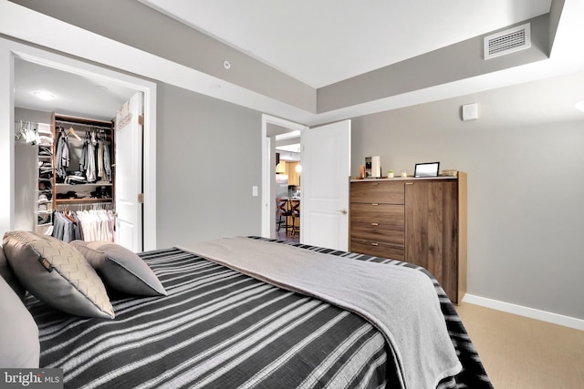 carpeted bedroom featuring a walk in closet and a closet