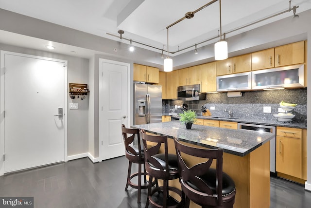 kitchen featuring appliances with stainless steel finishes, rail lighting, sink, a center island, and hanging light fixtures