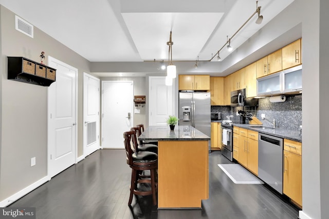 kitchen with a center island, light brown cabinets, stainless steel appliances, sink, and pendant lighting