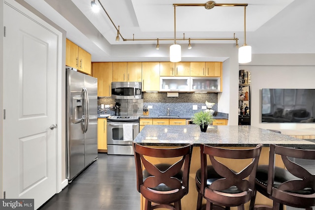 kitchen featuring sink, light brown cabinetry, stainless steel appliances, and hanging light fixtures