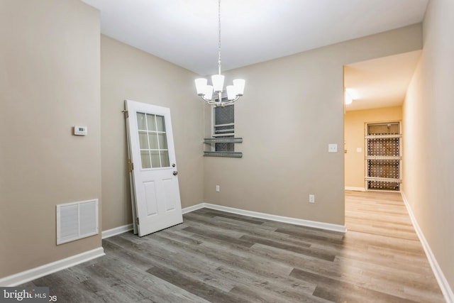 unfurnished dining area featuring wood-type flooring and a chandelier