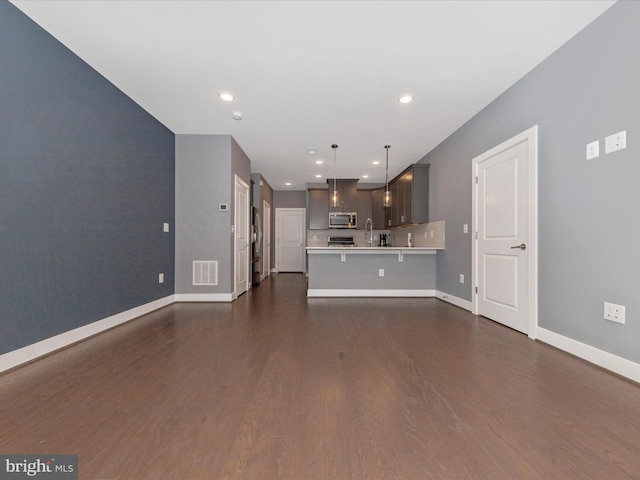 unfurnished living room featuring dark wood-type flooring and sink