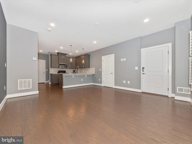 unfurnished living room featuring sink and dark wood-type flooring