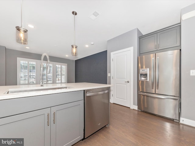 kitchen featuring sink, stainless steel appliances, decorative light fixtures, and gray cabinets