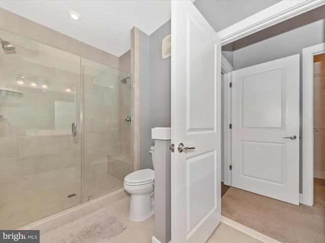 bathroom featuring toilet, a shower with shower door, and tile patterned floors