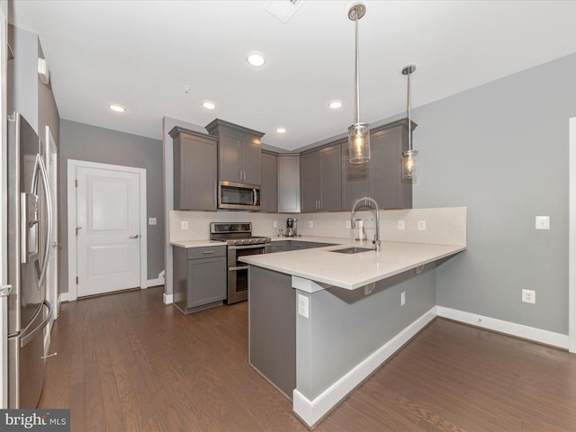 kitchen featuring sink, decorative light fixtures, kitchen peninsula, backsplash, and appliances with stainless steel finishes