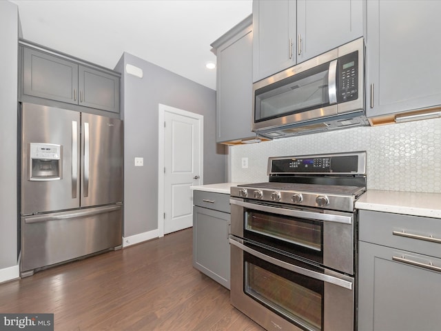 kitchen featuring stainless steel appliances, dark hardwood / wood-style flooring, gray cabinets, and decorative backsplash