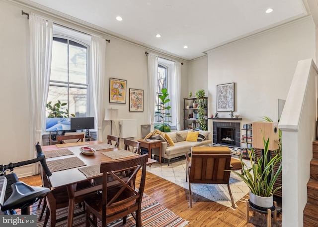 dining area with a wealth of natural light, crown molding, and light hardwood / wood-style floors