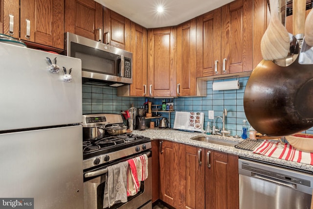 kitchen with light stone countertops, sink, stainless steel appliances, and tasteful backsplash