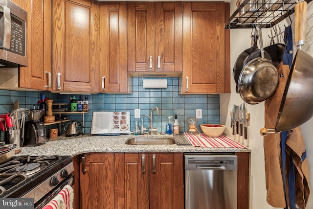 kitchen featuring appliances with stainless steel finishes, tasteful backsplash, light stone counters, and sink