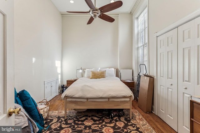 bedroom with ceiling fan, a closet, ornamental molding, and hardwood / wood-style flooring