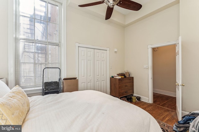 bedroom with a closet, multiple windows, dark hardwood / wood-style floors, and ceiling fan