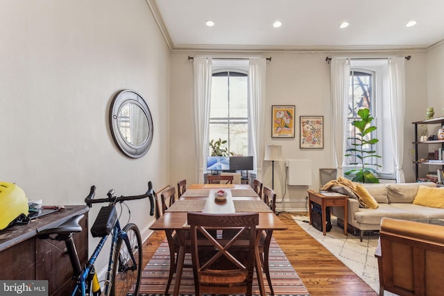 dining area featuring wood-type flooring and crown molding